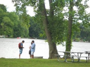 People standing near treees and lake